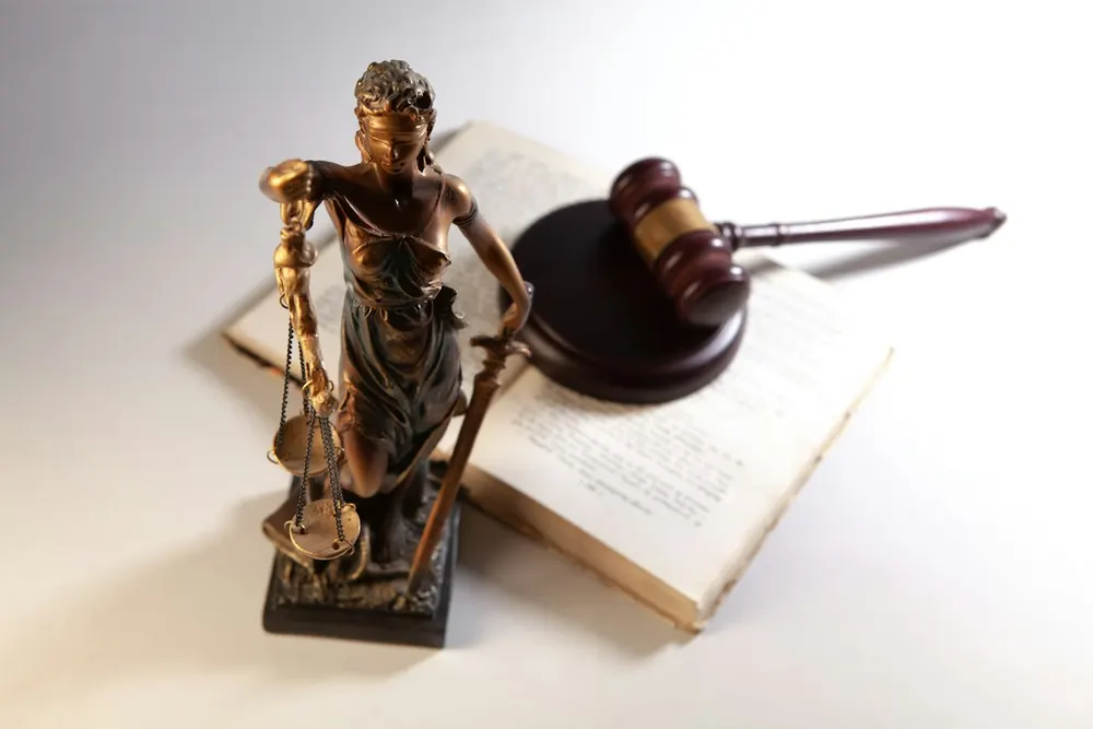 Estatua de la justicia junto a un libro abierto y un martillo de madera