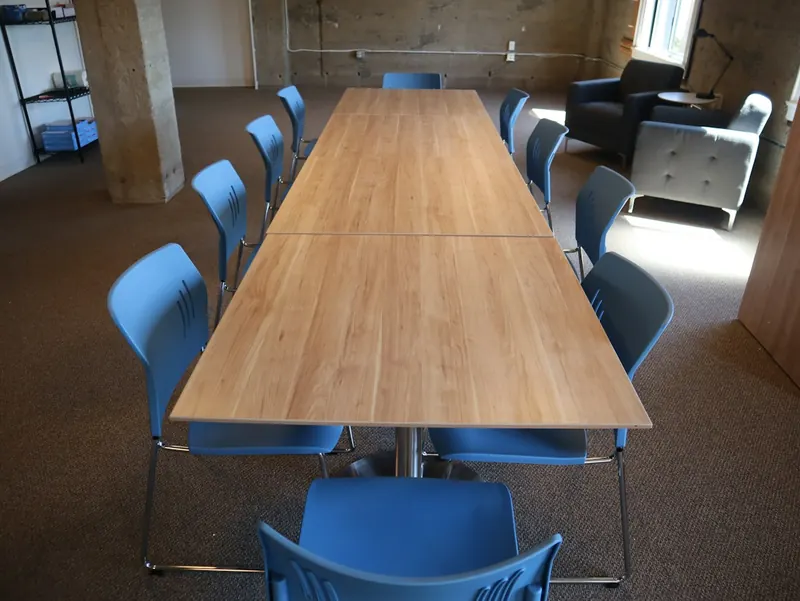 Sala de reuniones con una mesa larga de madera y sillas azules
