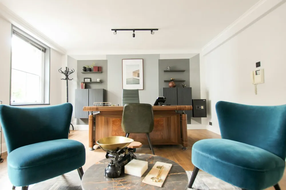 Espacio de consulta luminoso con sillones, escritorio y bibliotecas